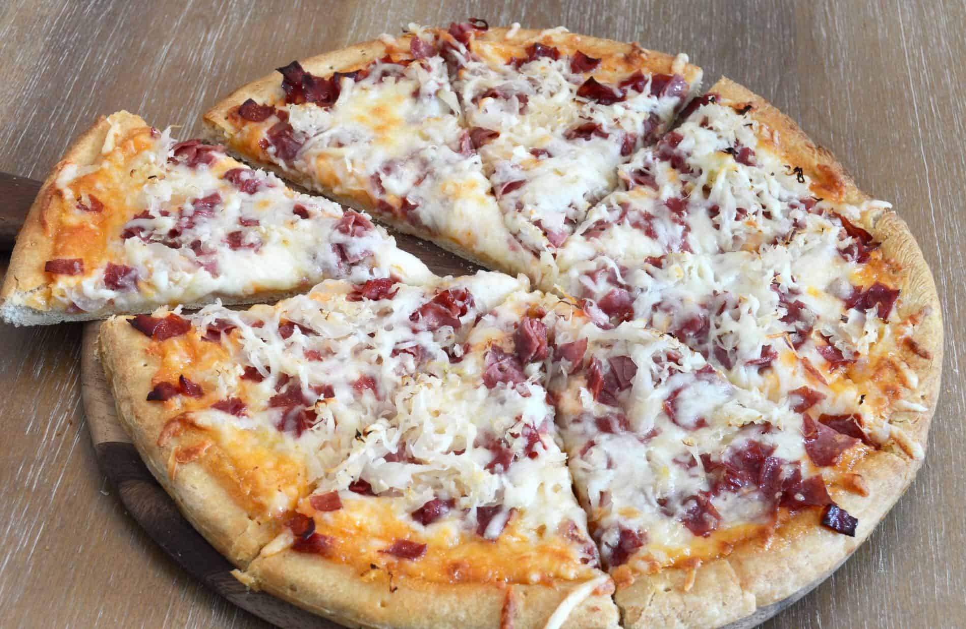 Reuben pizza recipe made with Jimmy's Thousand Island Dressing, corned beef, sauerkraut, and Swiss cheese.